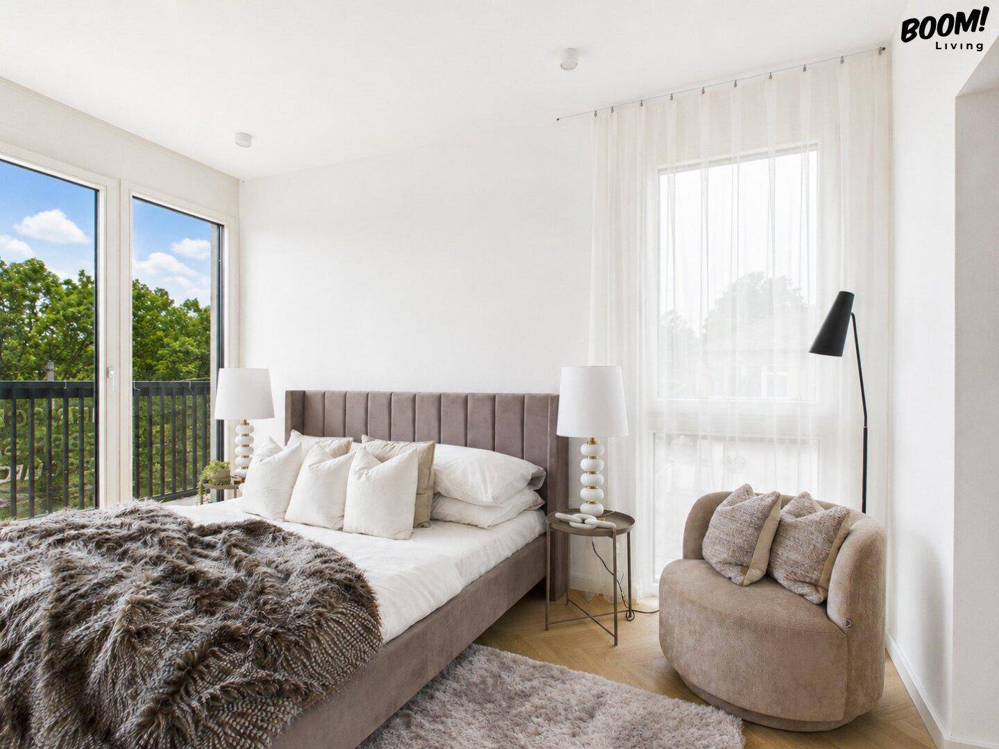 Helles Schlafzimmer mit großem Bett, Balkonzugang und bodentiefen Fenstern.
