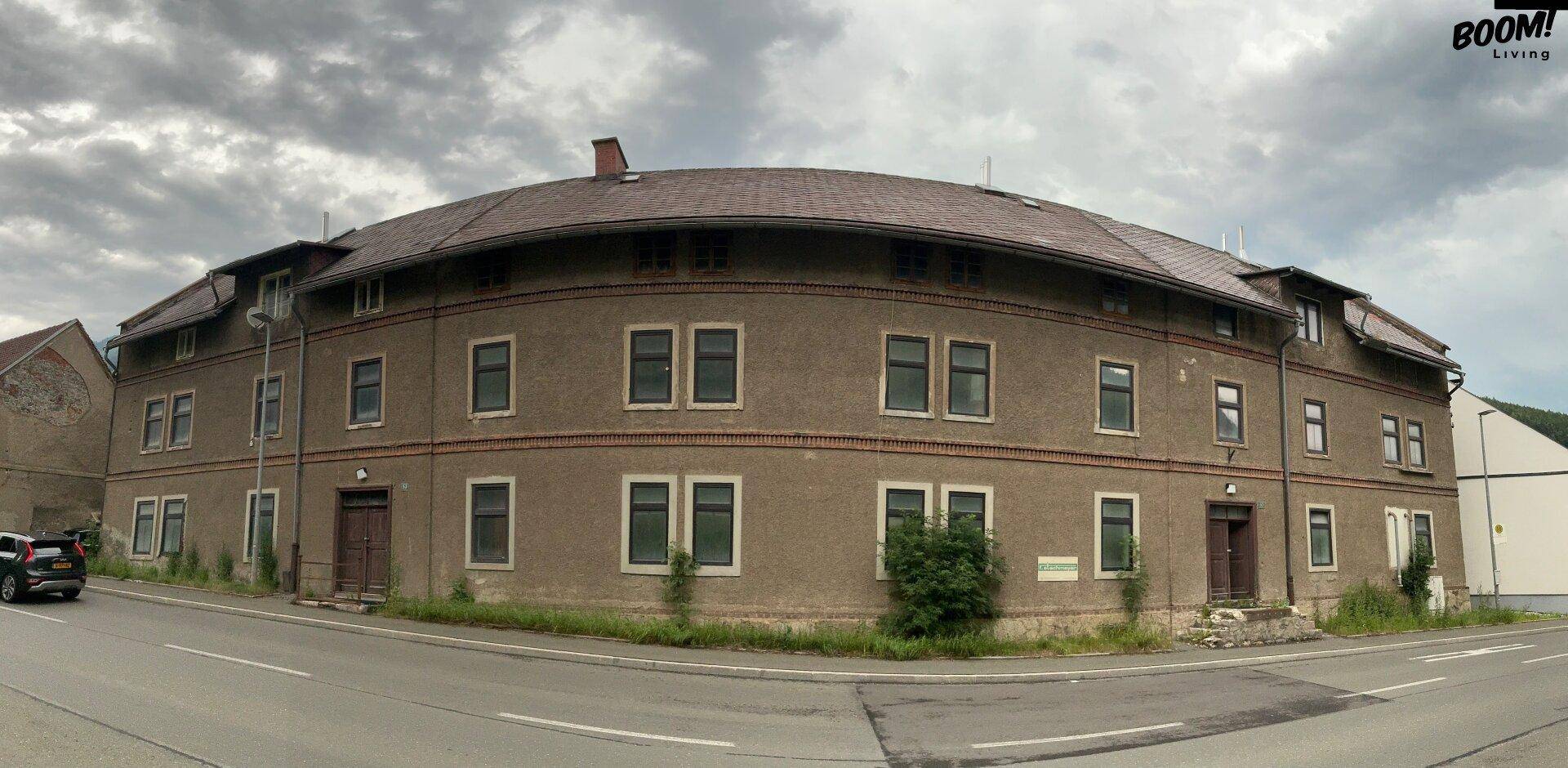 Panoramablick auf die geschwungene Fassade des historischen Gebäudes unter bewölktem Himmel.