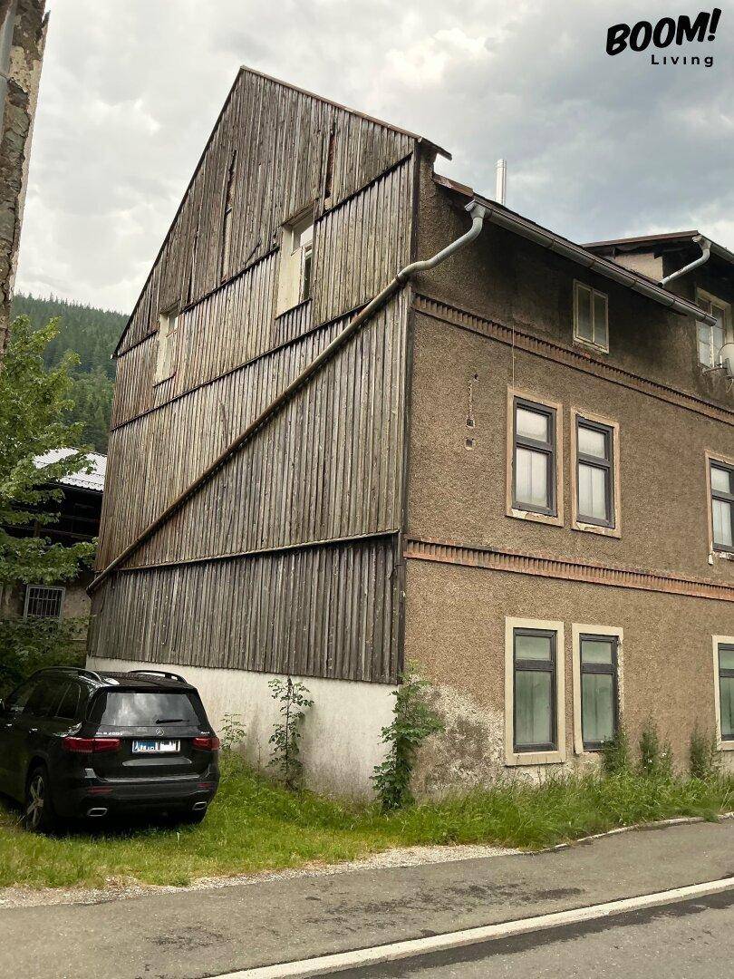 Seitenansicht des Gebäudes mit einer markanten Holzverkleidung und einem geparkten Auto davor.