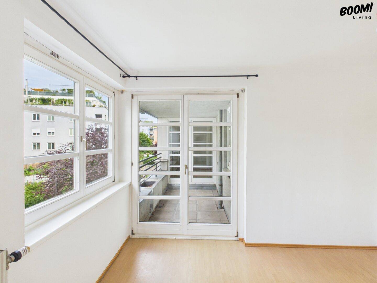 Geräumiger, leerer Raum mit großen Fenstern und Zugang zu einem Balkon.