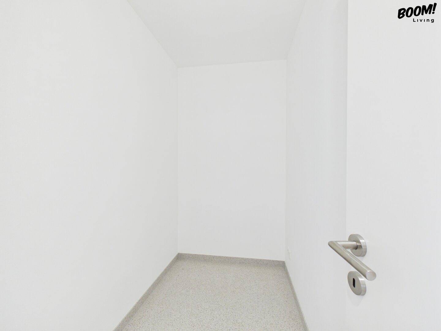 Kleiner, leerer Abstellraum mit weißen Wänden und grauem Fliesenboden, ideal für zusätzlichen Stauraum.