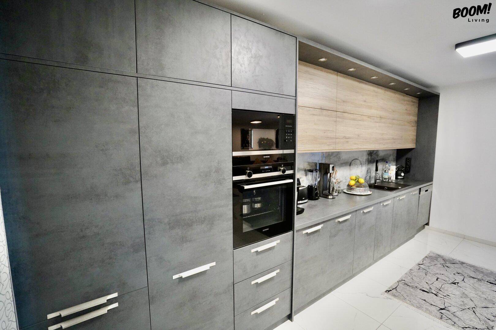 Elegante Küche mit grauen Unterschränken, integriertem Backofen und Holz-Oberschränken.