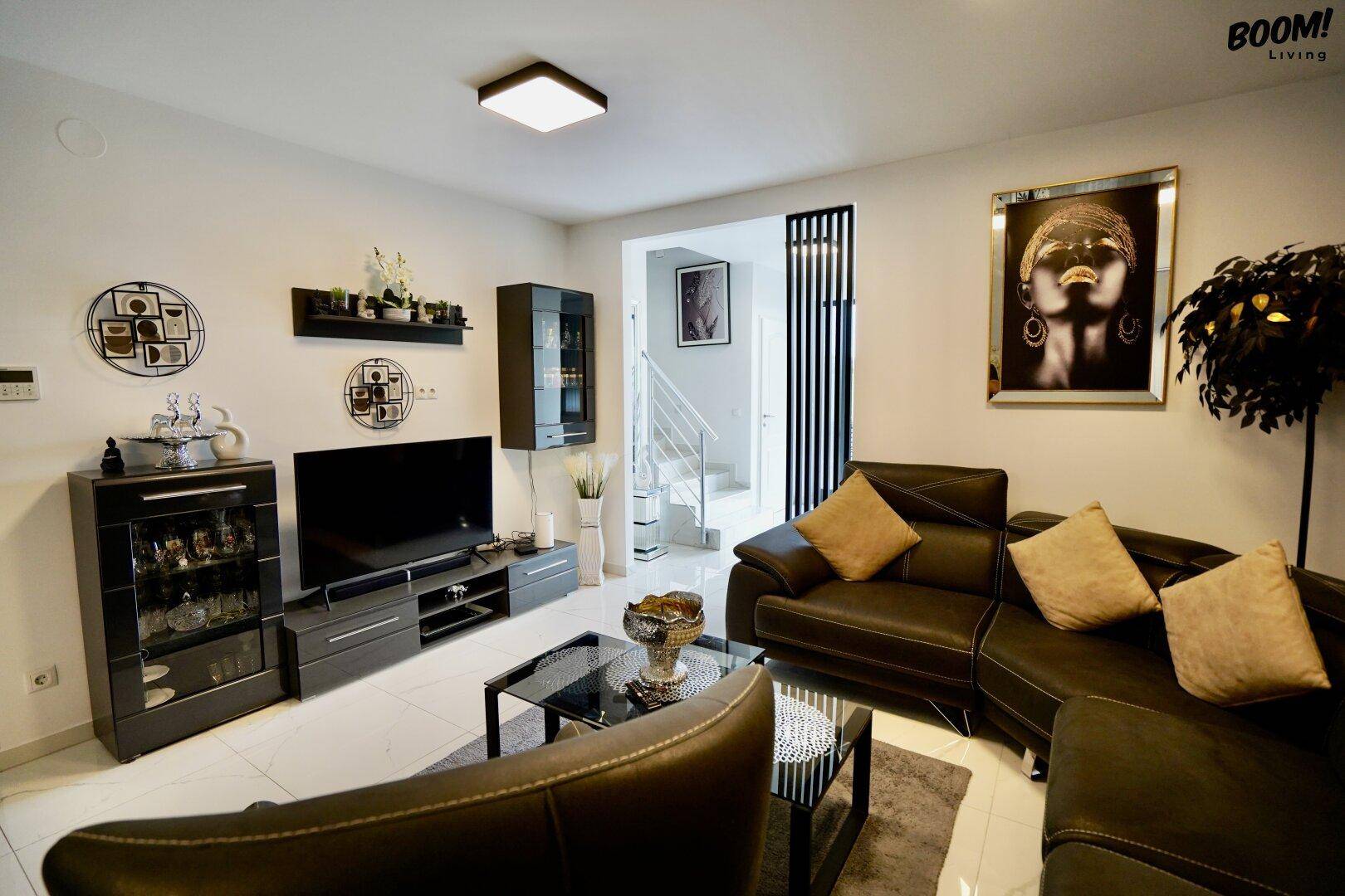 Modernes Wohnzimmer mit großem Ecksofa, TV-Möbeln und Glastisch auf glänzenden Fliesen.