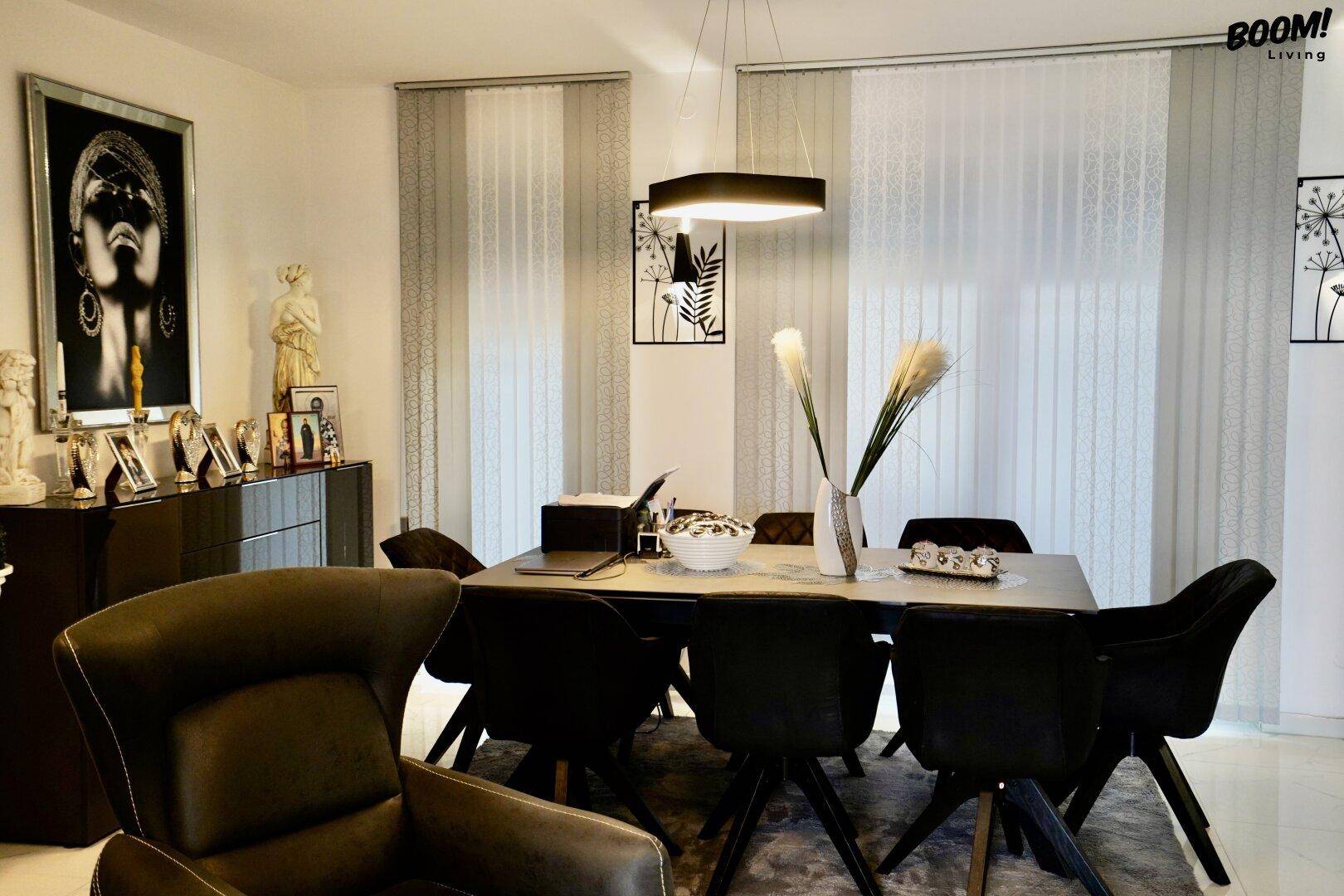 Eleganter Essbereich mit großem Esstisch und schwarzen Stühlen, ergänzt durch ein dunkles Sideboard.