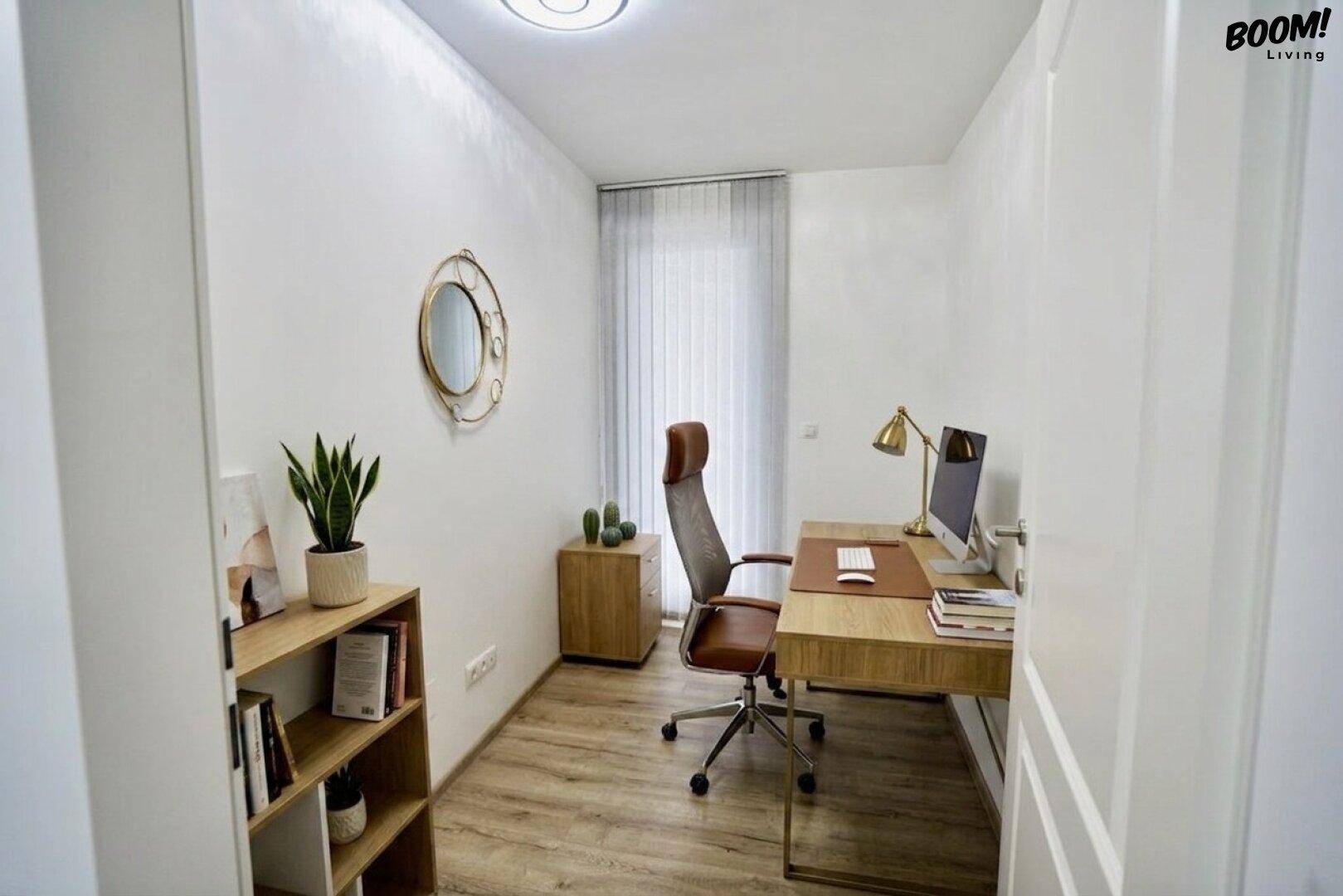 Helles Arbeitszimmer mit Holzschreibtisch, Bürostuhl und Bücherregal für eine produktive Umgebung.