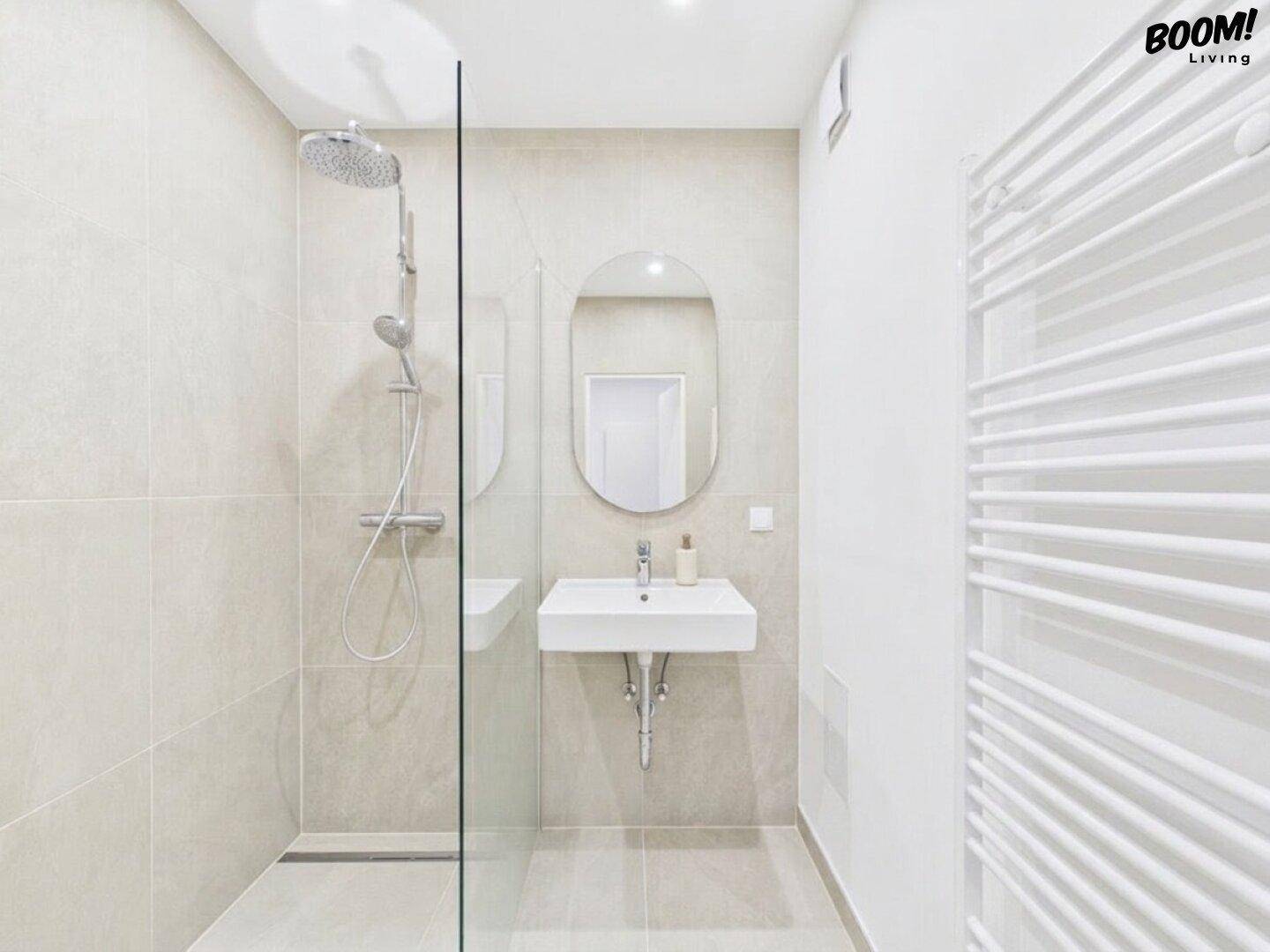 Modernes Badezimmer mit ebenerdiger Dusche, Glaswand und beheiztem Handtuchhalter.