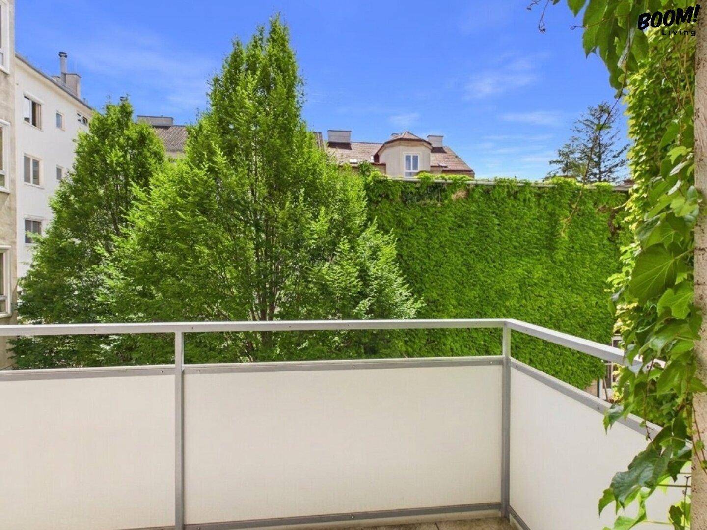 Balkon mit moderner Verkleidung und Blick auf die grüne Umgebung und Nachbargebäude.
