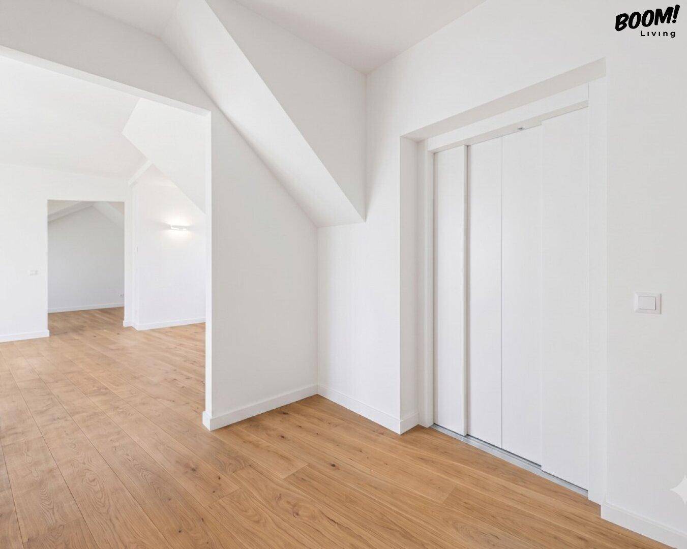 Heller Flur mit Holzboden und einer modernen Aufzugstür, führt zu weiteren Räumen.
