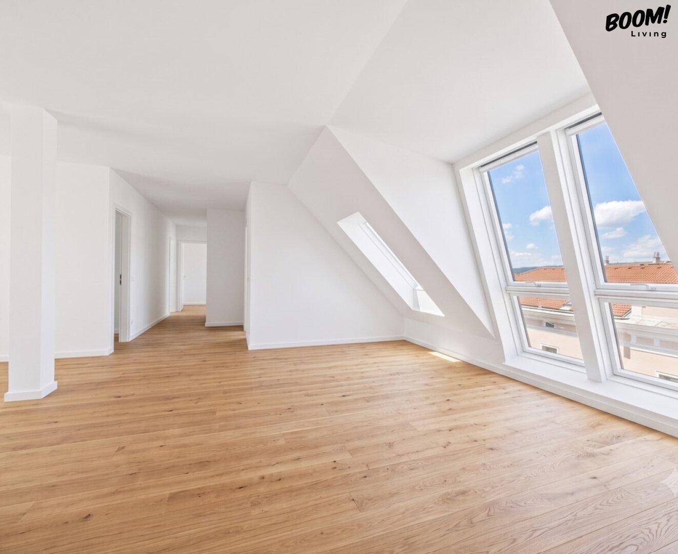 Geräumiger, heller Dachgeschossraum mit Holzboden und großen Fenstern.