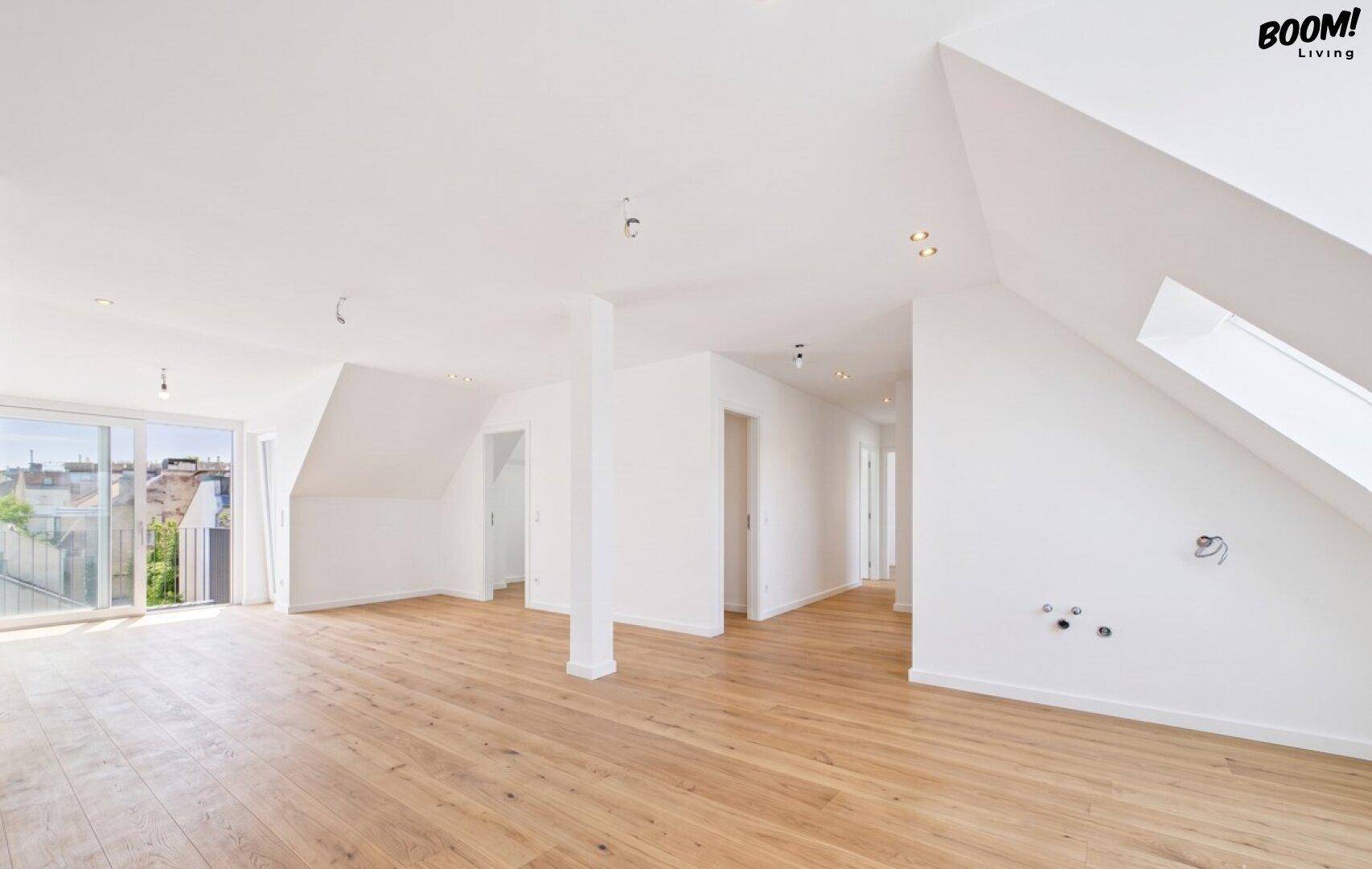 Geräumiger, heller Dachgeschossraum mit Holzboden und Balkonzugang.