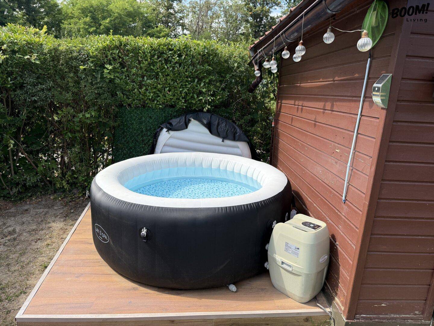 Whirlpool auf einer Holzplattform neben einem Holzschuppen, bereit für entspannte Stunden im Garten.