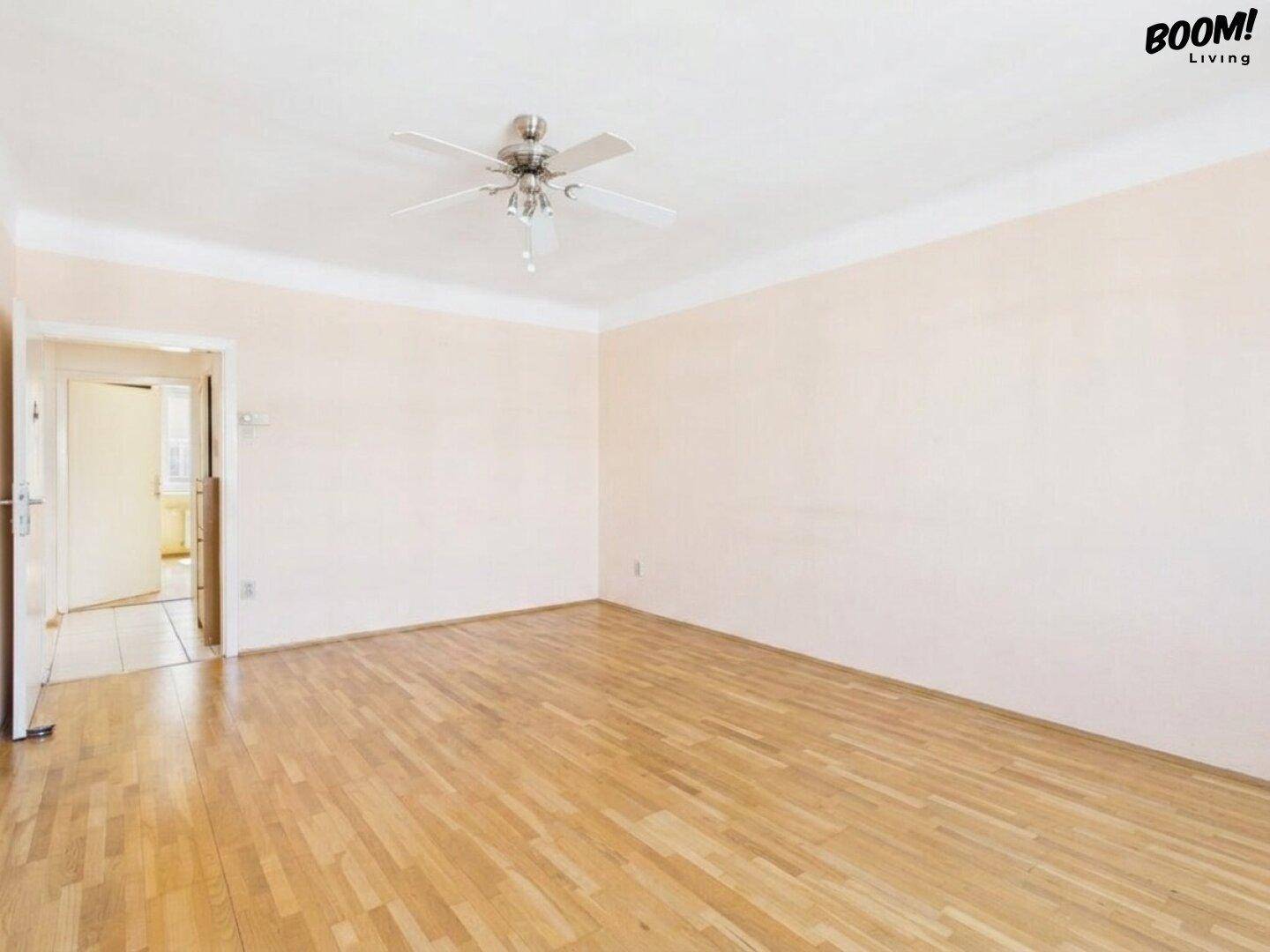Geräumiges, leeres Zimmer mit Parkettboden und Zugang zu einem weiteren Bereich.