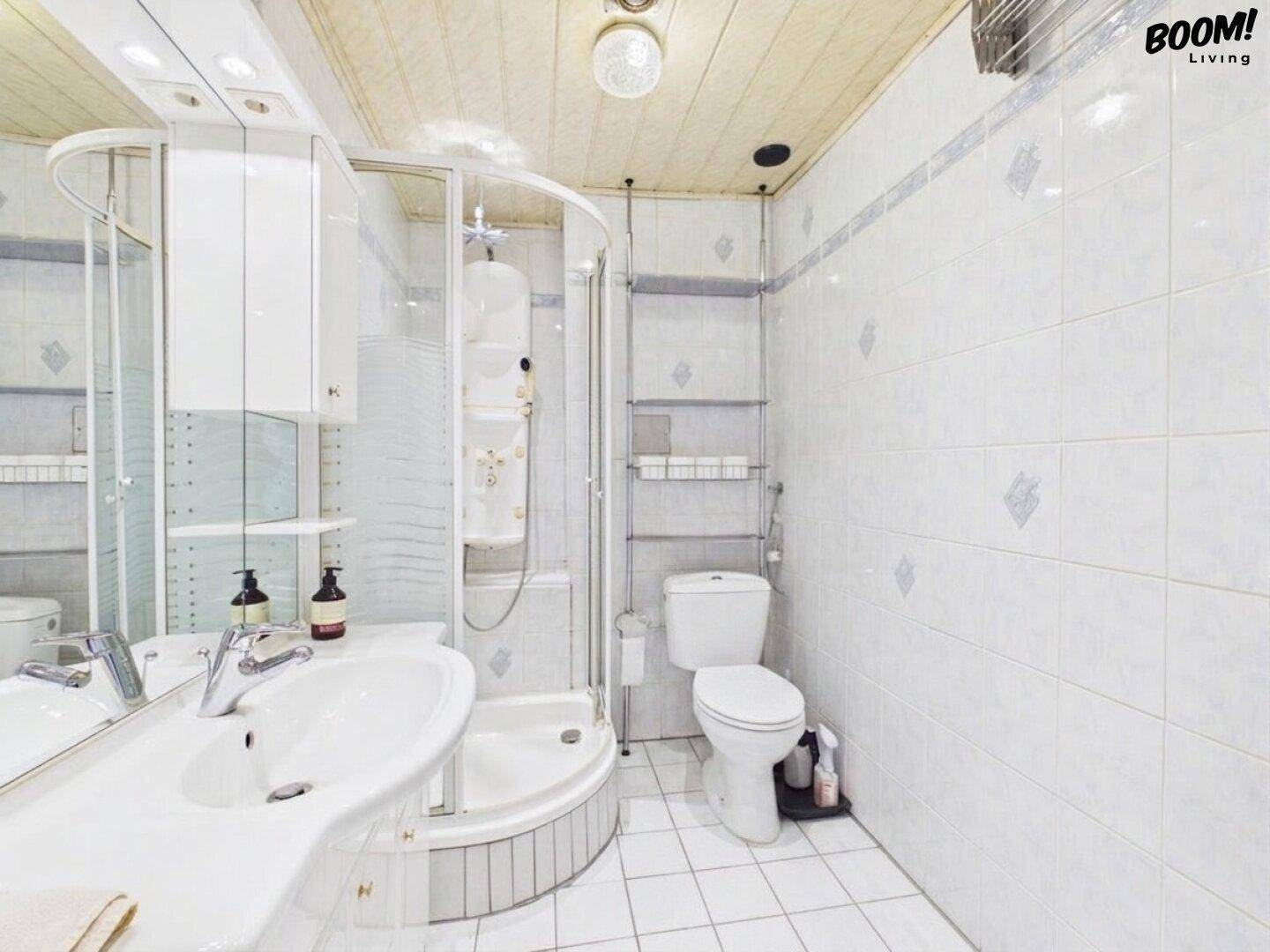 Helles Badezimmer mit Dusche, Waschbecken und weißen Fliesen.