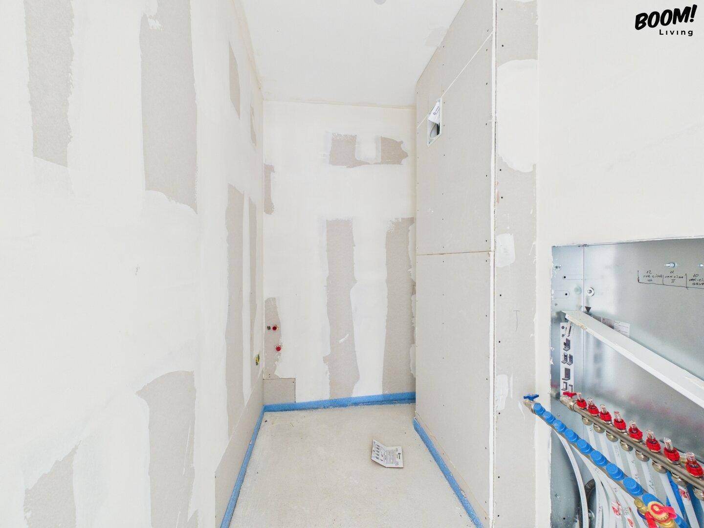 Unfertiges Badezimmer mit sichtbaren Sanitärinstallationen und vorbereiteten Wänden für Fliesen.