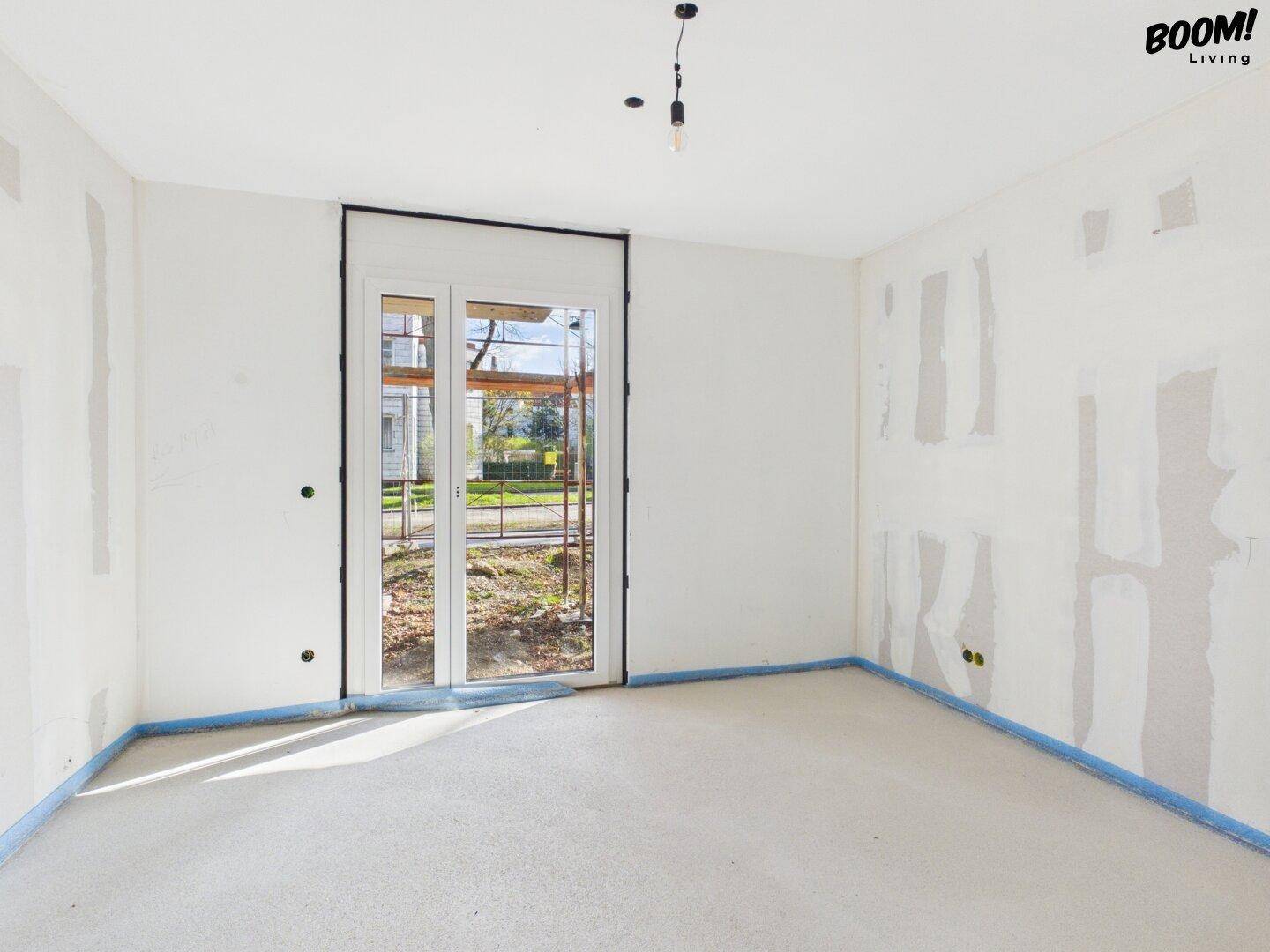 Unfertiges Zimmer mit Zugang nach draußen und vorbereiteten Wänden für den weiteren Ausbau.