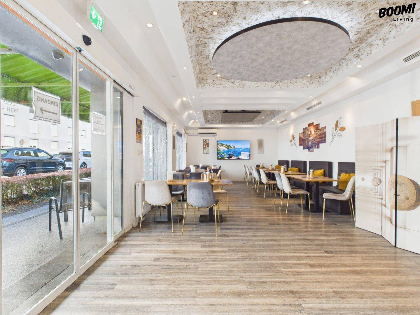 Heller Restaurant-Speisesaal mit modernen Tischen, Stühlen und einer dekorativen Decke.