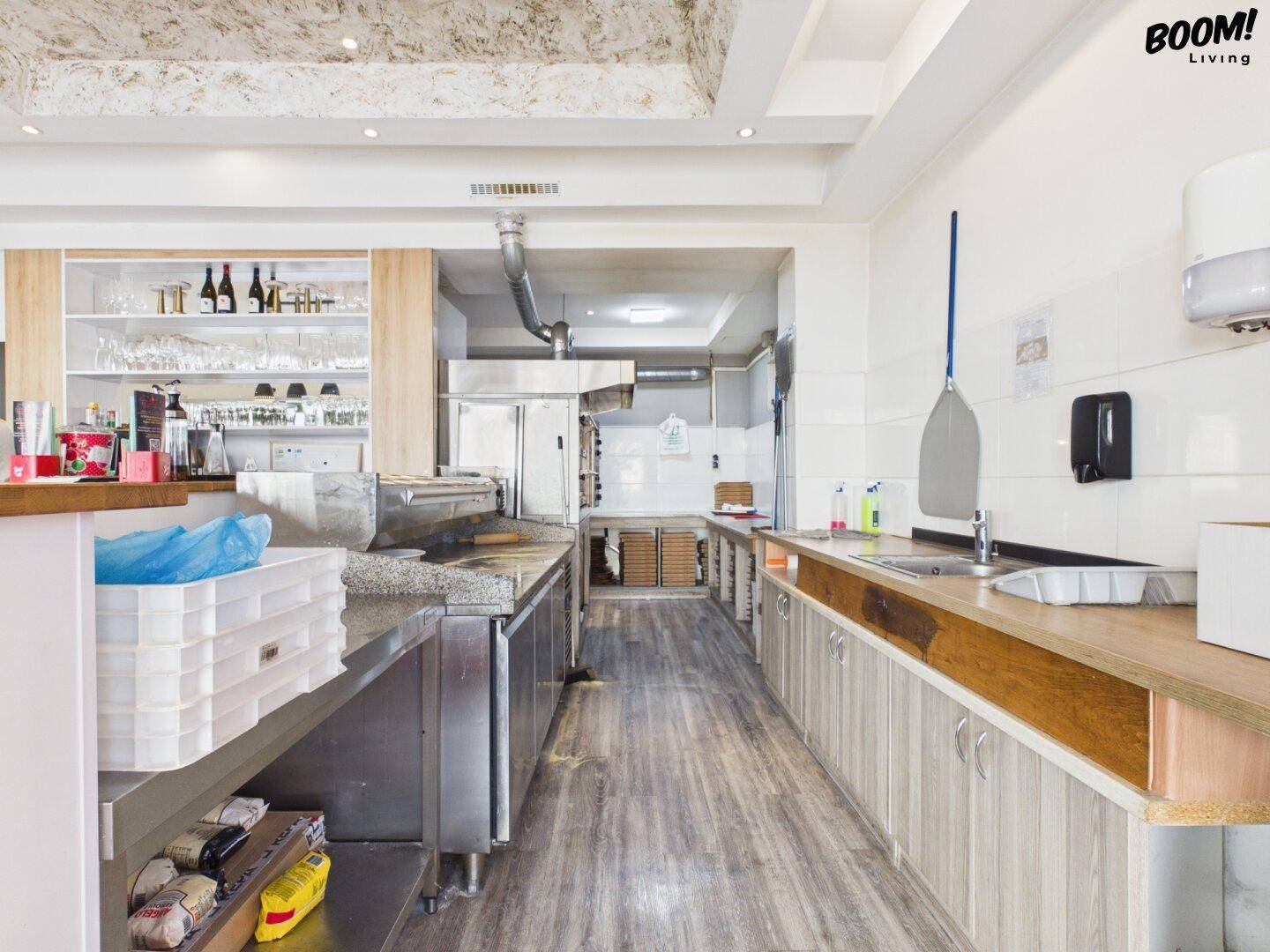 Professionelle Restaurantküche mit Edelstahlgeräten, Arbeitsflächen und Regalen für die Zubereitung.