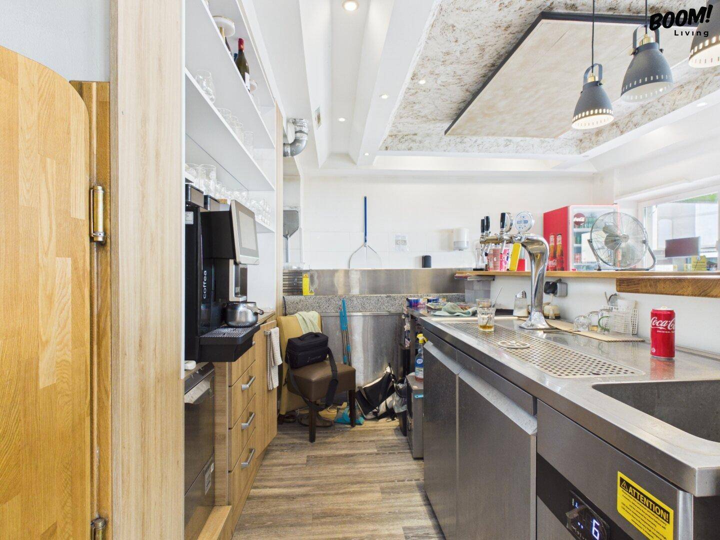 Thekenbereich des Restaurants mit Zapfanlage, Kaffeemaschine und Regalen für Gläser.