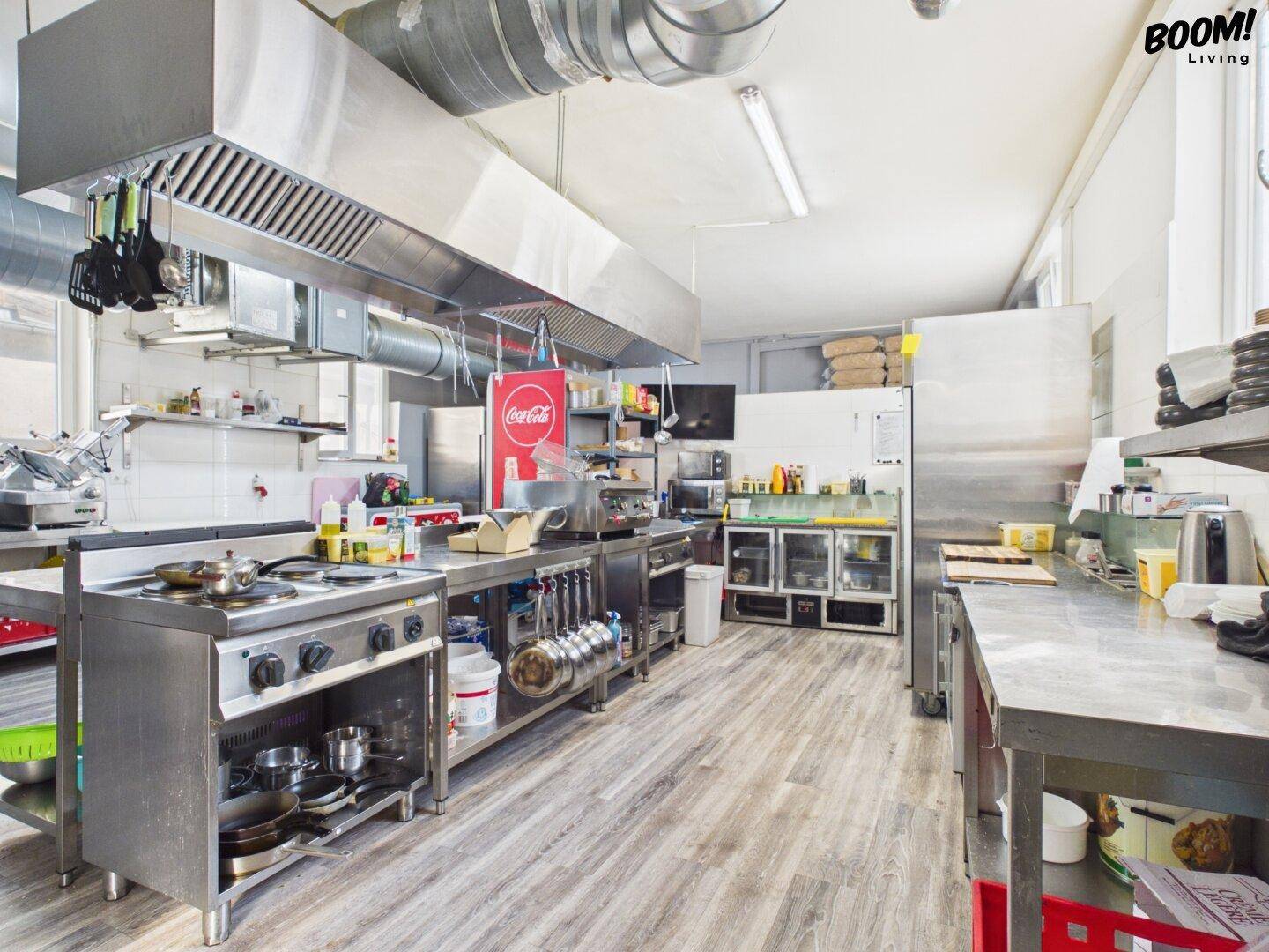 Große, voll ausgestattete Restaurantküche mit professionellen Edelstahlgeräten und Abluftsystem.