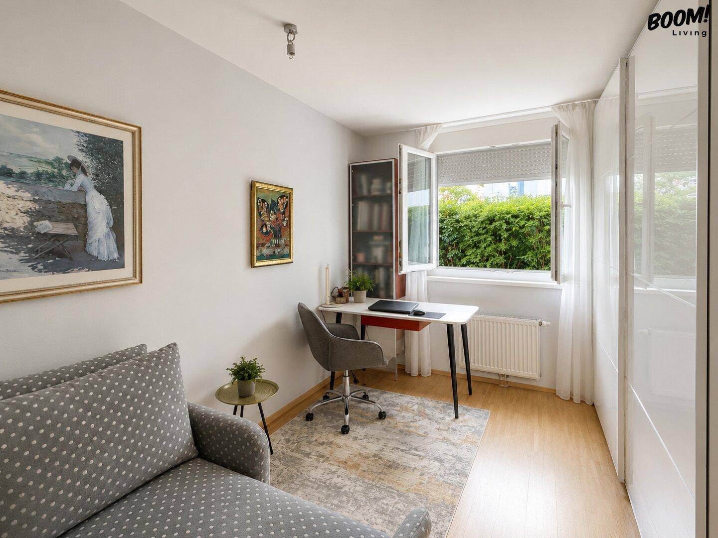 Gemütliches Arbeitszimmer mit Schreibtisch, Sofa und Fenster mit Blick auf die grüne Umgebung.