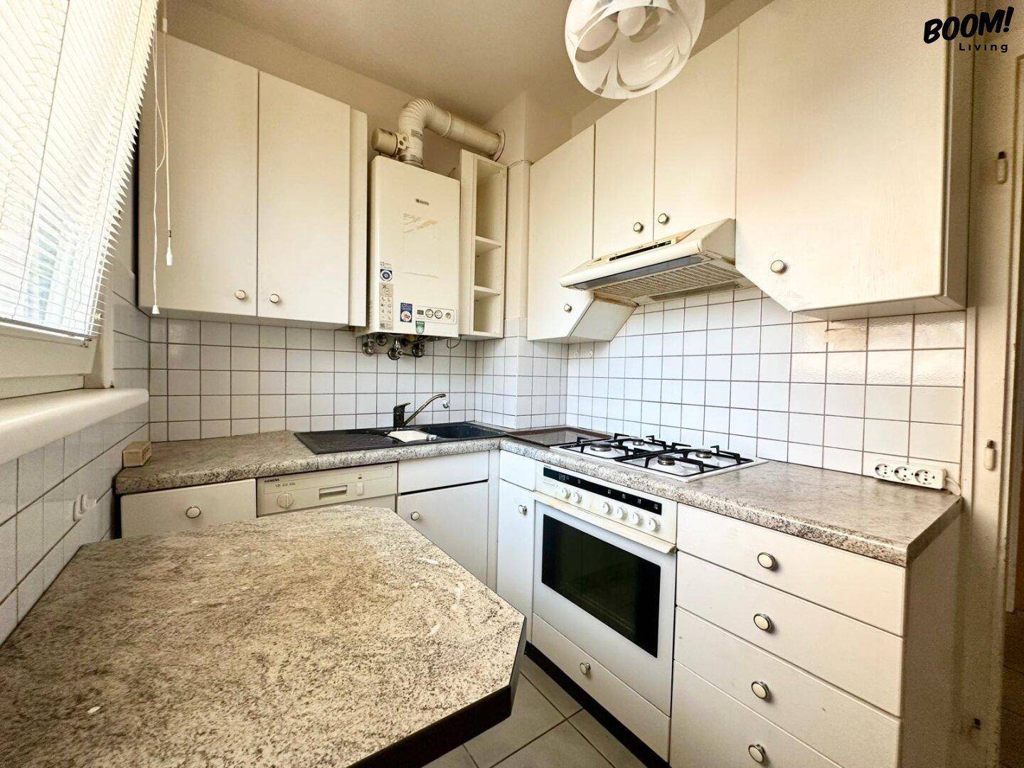 Funktionale Küche mit weißen Schränken, Gasherd, Backofen und einem Warmwasserboiler.