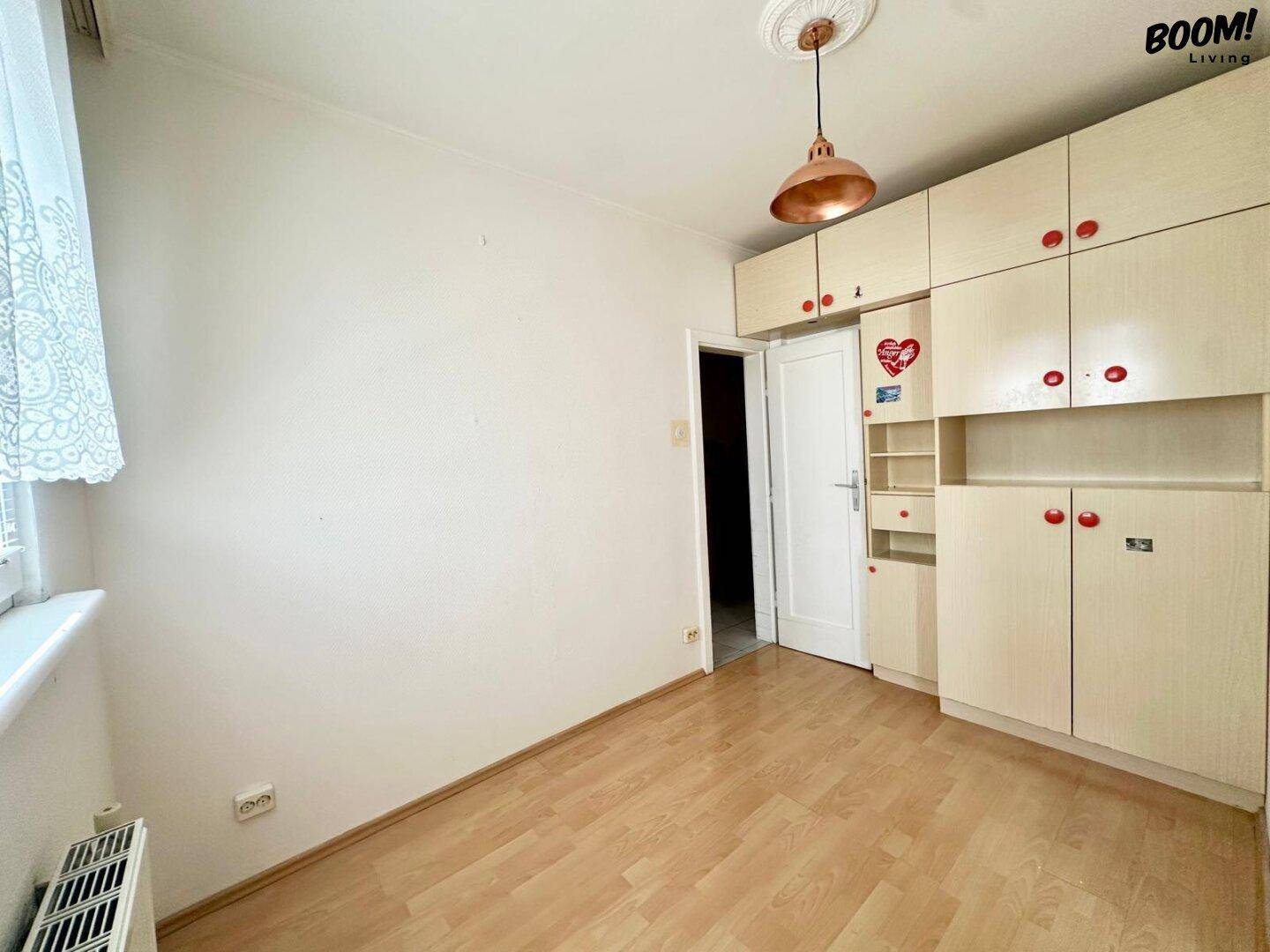 Schlafzimmer mit Laminatboden und einem großen Einbauschrank, der viel Stauraum bietet.