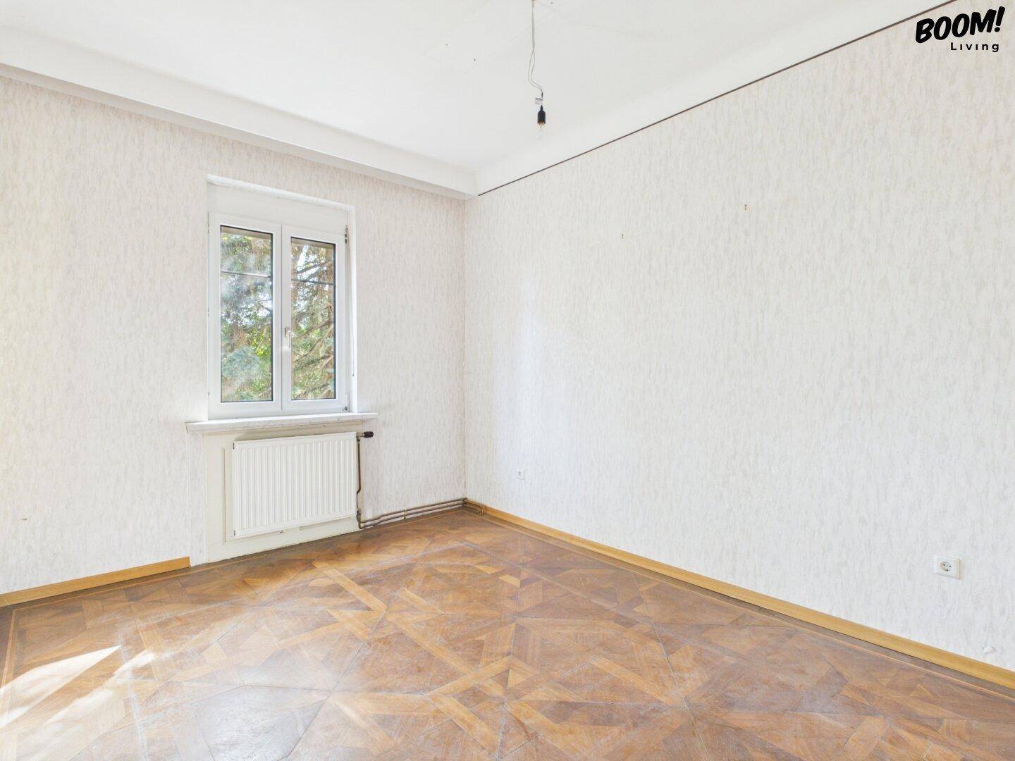 Helles Schlafzimmer mit Parkettboden und Fensterblick ins Grüne, bietet Ruhe und Komfort.