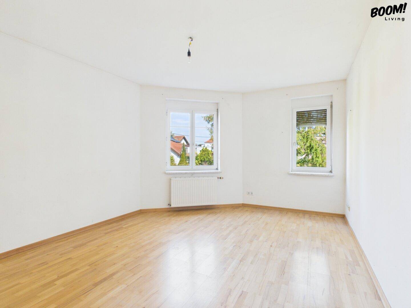 Geräumiges Schlafzimmer mit Parkettboden und zwei Fenstern, bietet viel natürliches Licht.