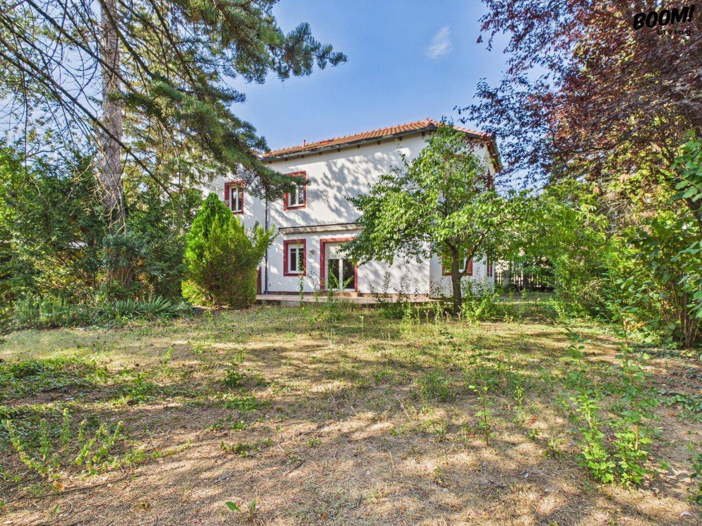 Rückseite des Hauses mit großem, naturbelassenem Gartenbereich und altem Baumbestand.