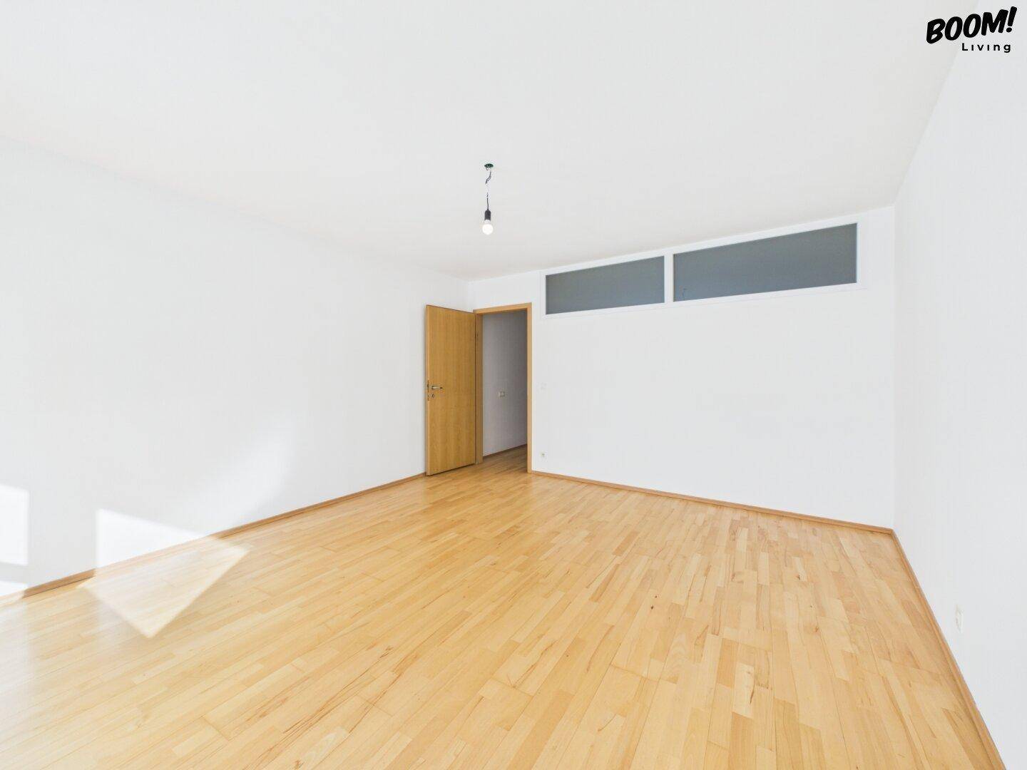 Geräumiges Wohnzimmer mit Parkettboden und Oberlichtfenstern für zusätzliches Licht.