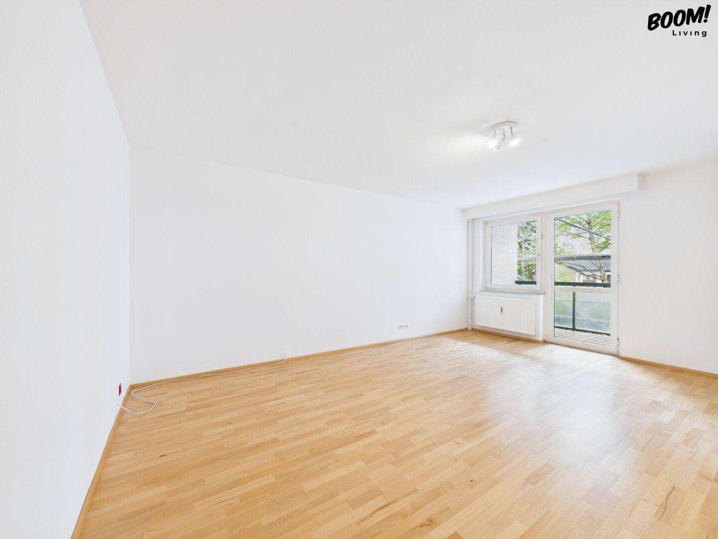 Geräumiges Schlafzimmer mit Parkettboden und Fenster mit Zugang zu einem Balkon.