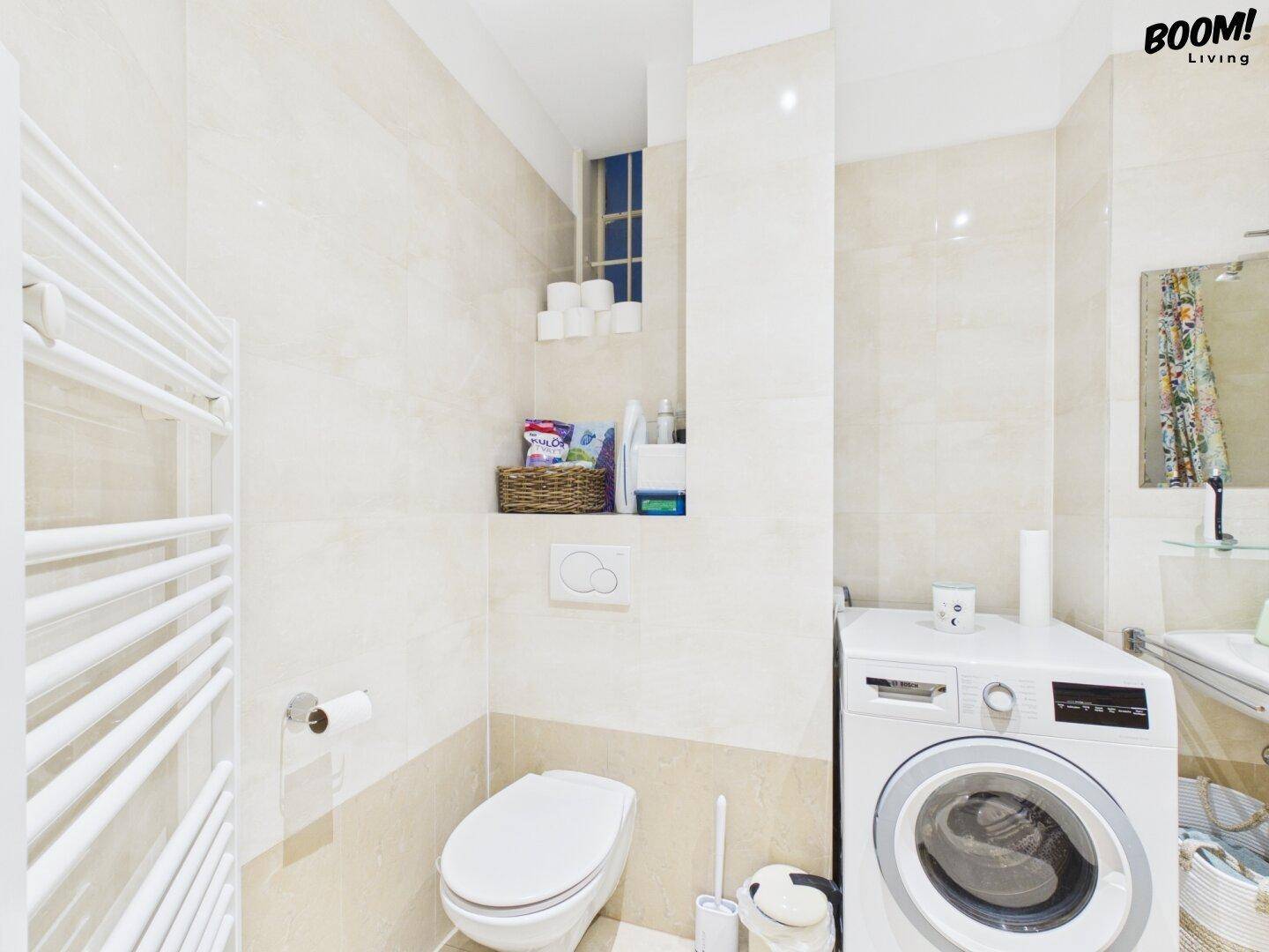 Funktionales Badezimmer mit Toilette, beheiztem Handtuchhalter und Waschmaschine.