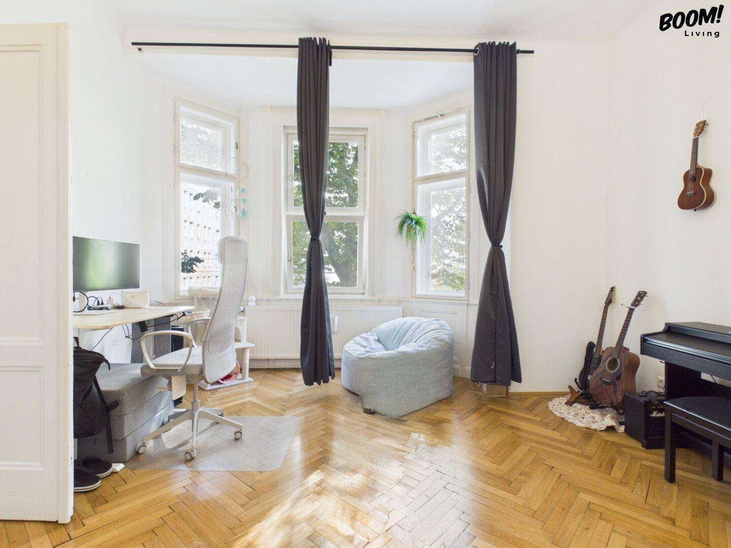 Helles Arbeitszimmer mit Schreibtisch, Bürostuhl und großen Fenstern mit Blick ins Grüne.
