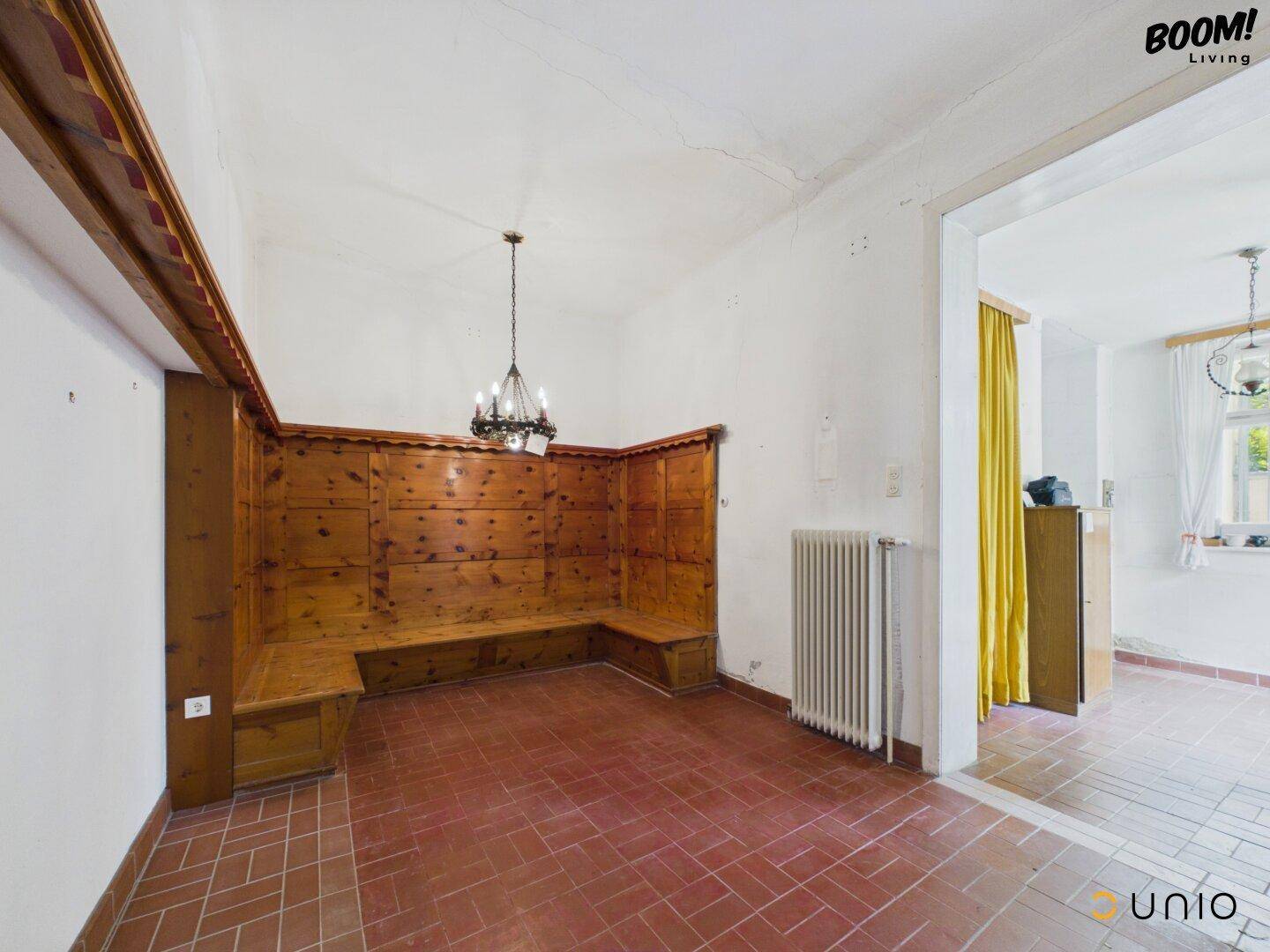 Traditioneller Essbereich mit Holzbänken, Terrakottafliesen und Kronleuchter.