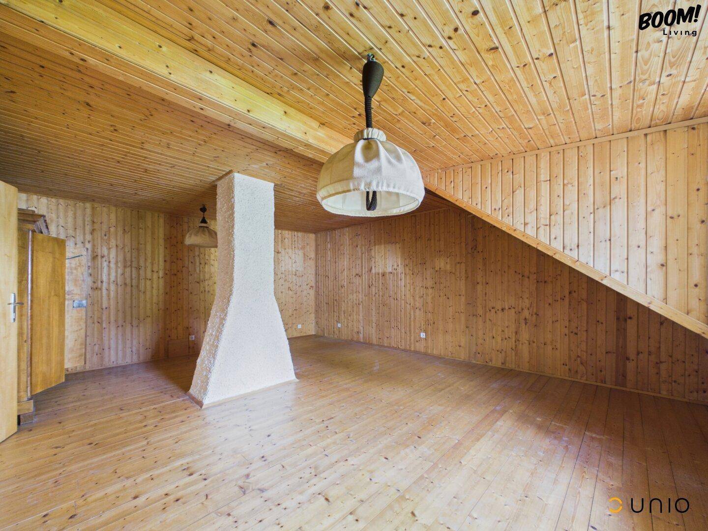 Geräumiger Innenraum mit Holzverkleidung, Holzdielenboden und einem zentralen Pfeiler.