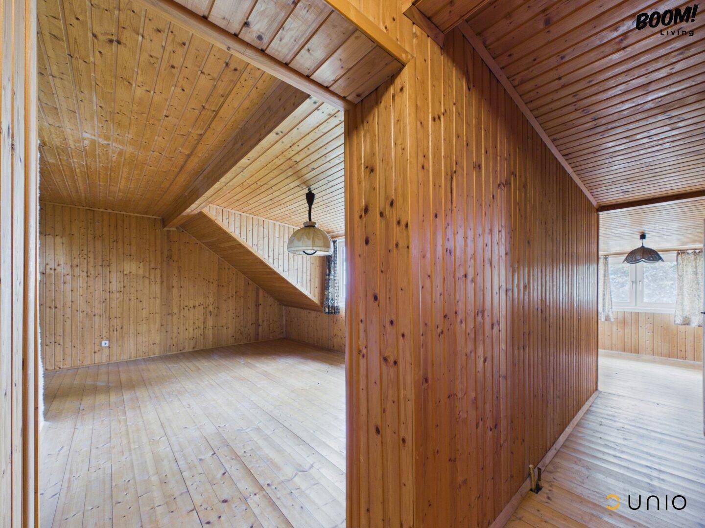 Innenraum mit umfassender Holzverkleidung an Wänden und Decke sowie Holzdielenboden.