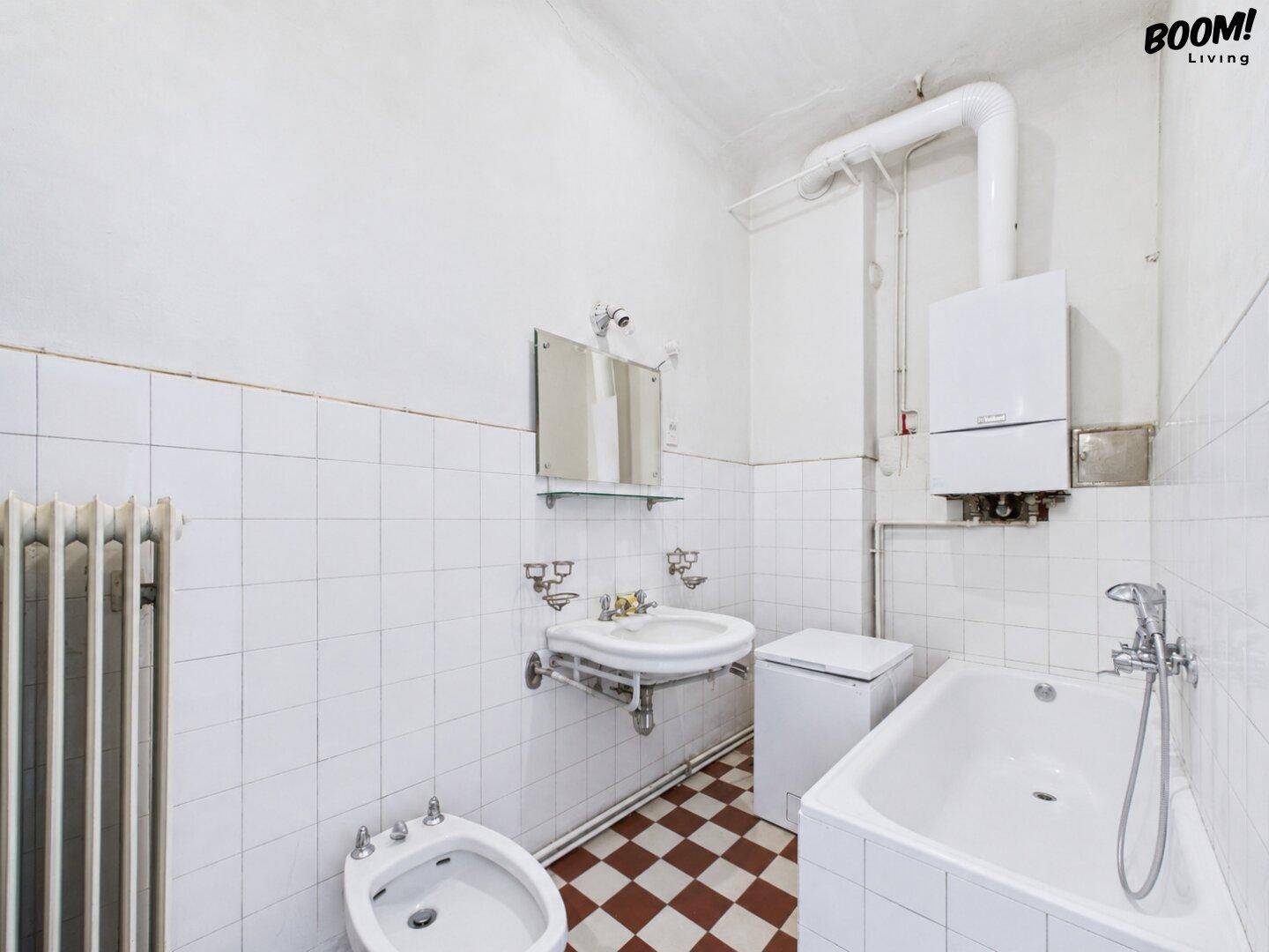 Badezimmer mit Badewanne, Bidet, Waschbecken und weiß-roten Fliesen im Schachbrettmuster.