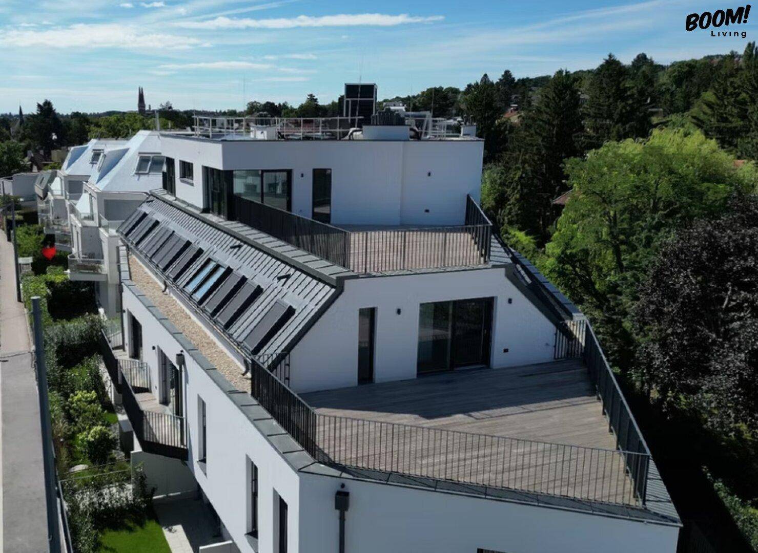 Ansicht der modernen Wohnanlage mit Dachterrassen und umliegender grüner Landschaft.