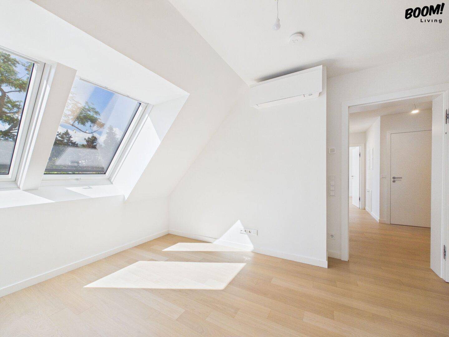Helles Schlafzimmer mit Dachschrägen, Holzboden und Dachfenstern.