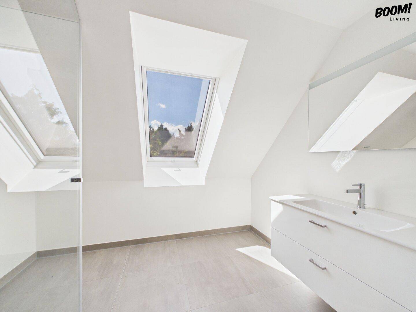 Modernes Badezimmer mit Waschtisch, Spiegel und Dachfenster.