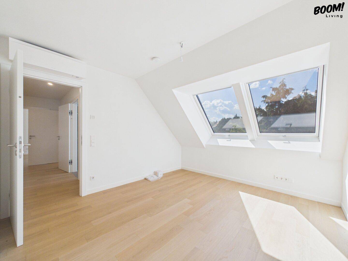 Helles Schlafzimmer mit Dachschrägen, Holzboden und zwei großen Dachfenstern.