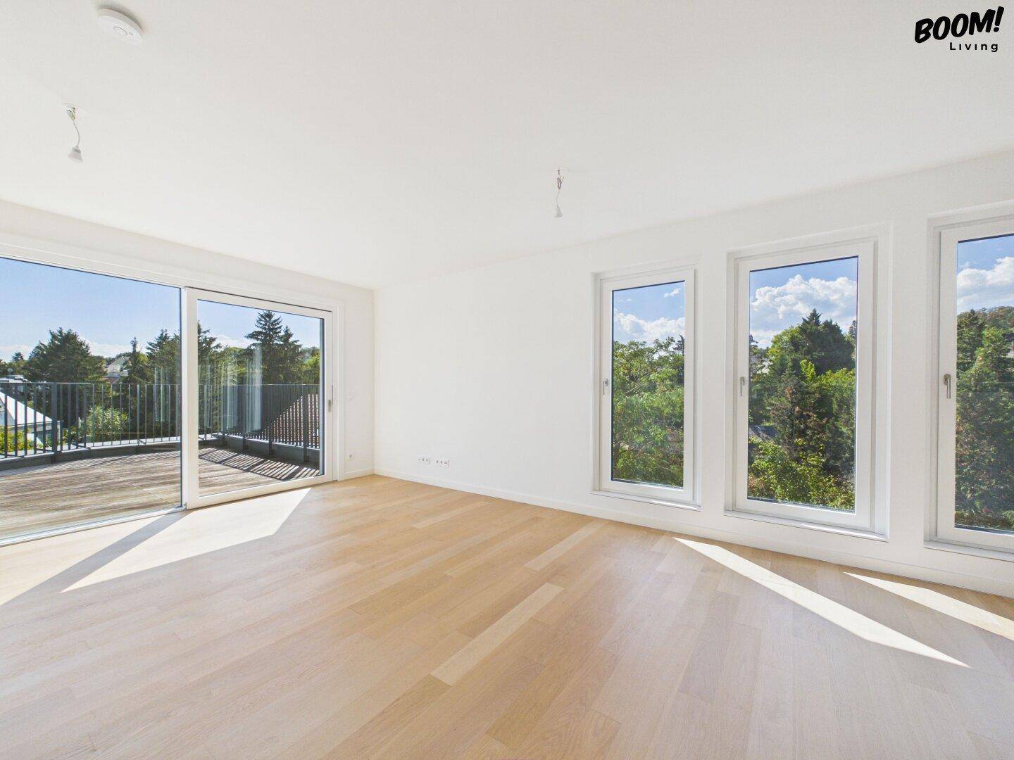 Helles Wohnzimmer mit Holzboden, großen Fenstern und Zugang zu einer Terrasse.