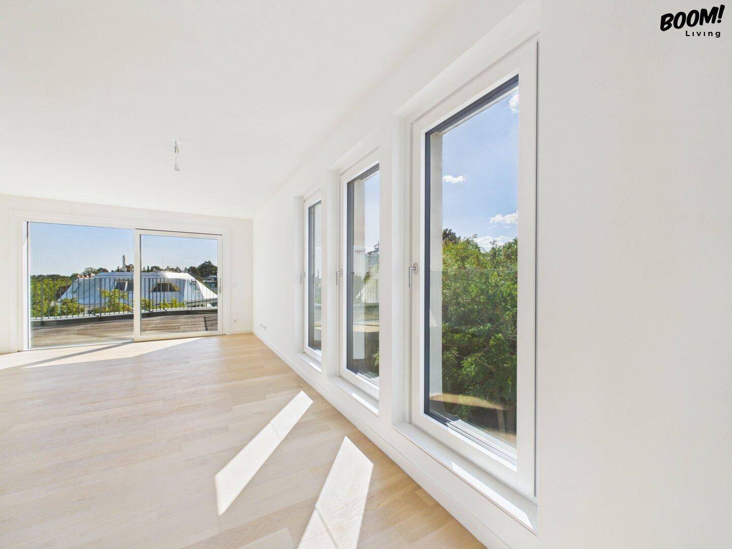 Geräumiges Wohnzimmer mit Holzboden, großen Fenstern und Zugang zur Terrasse.