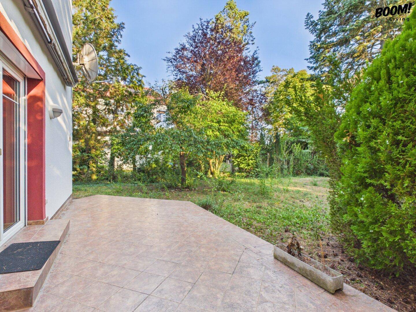 Geflieste Terrasse am Haus mit Blick auf den weitläufigen Gartenbereich.