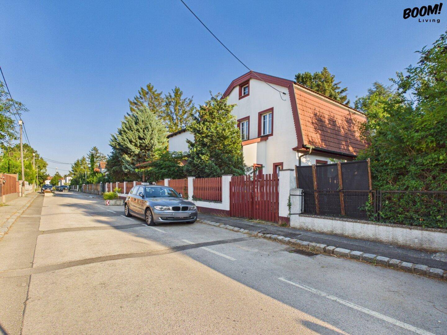 Ansicht des Hauses von der Straße mit Mansarddach und umliegender Wohnbebauung.