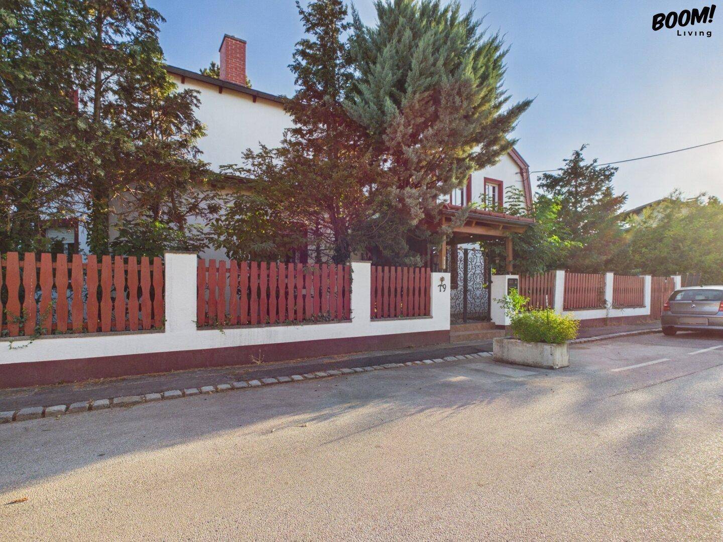 Vorderansicht des Hauses von der Straße mit rotem Holzzaun und Eingangsbereich.