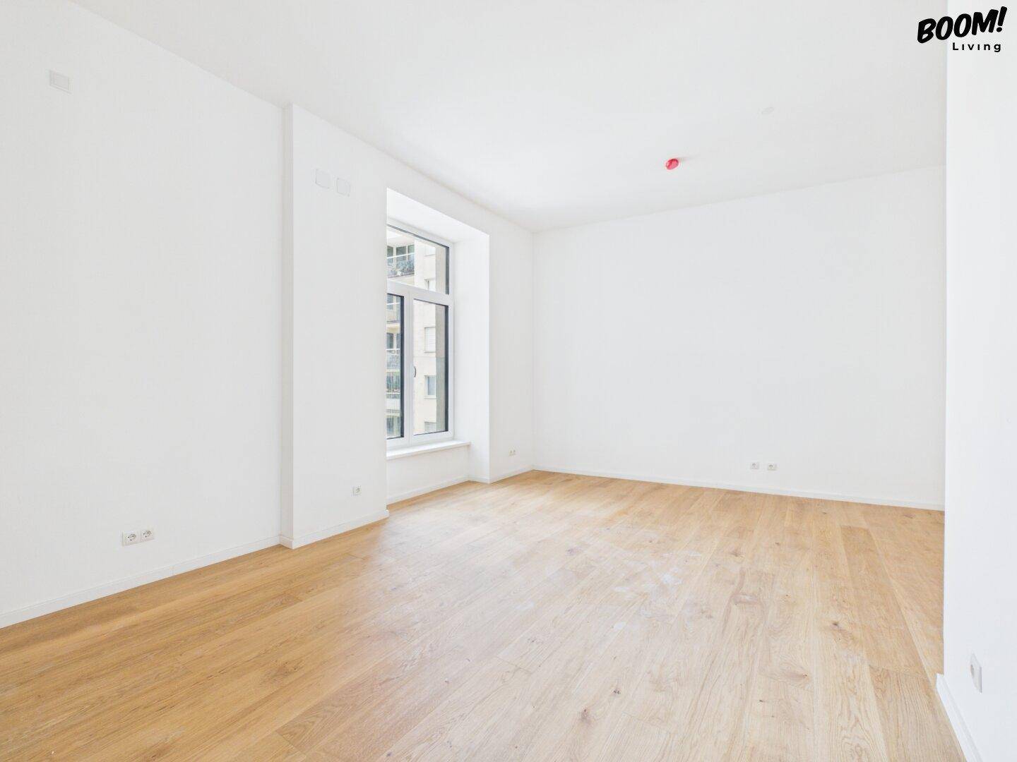 Unmöblierter Raum mit hellem Holzboden und Fenster, ideal für Schlaf- oder Arbeitszimmer.