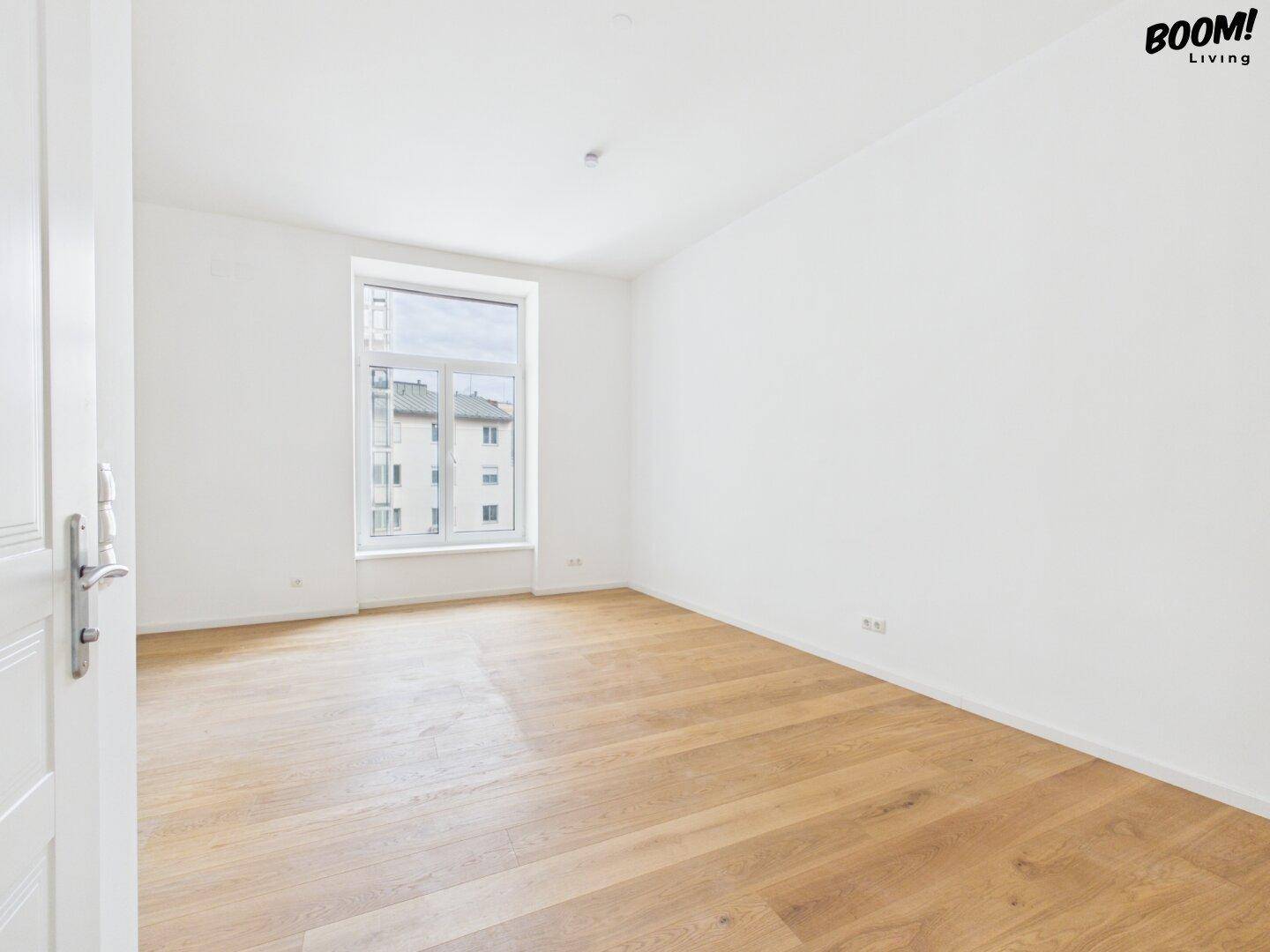 Großer, heller Raum mit Parkettboden und Fenster, bietet viel Tageslicht und eine offene Atmosphäre.