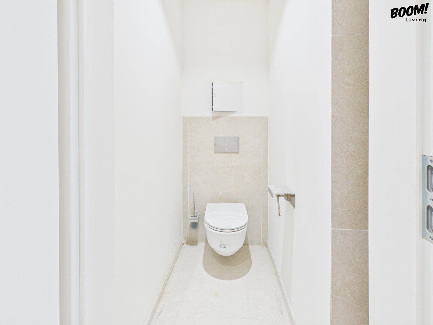 Separates WC mit wandhängender Toilette und modernen hellen Fliesen, minimalistisch gestaltet.