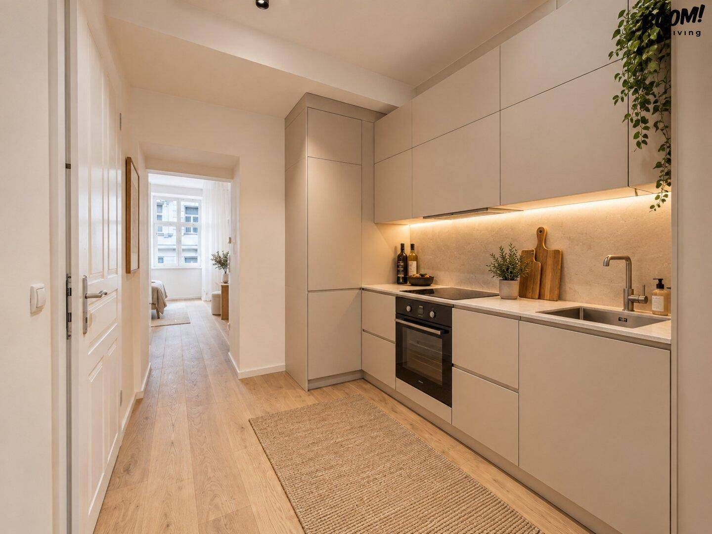Moderne Einbauküche in hellem Beige mit integrierten Geräten und Holzboden, die in einen Flur übergeht.